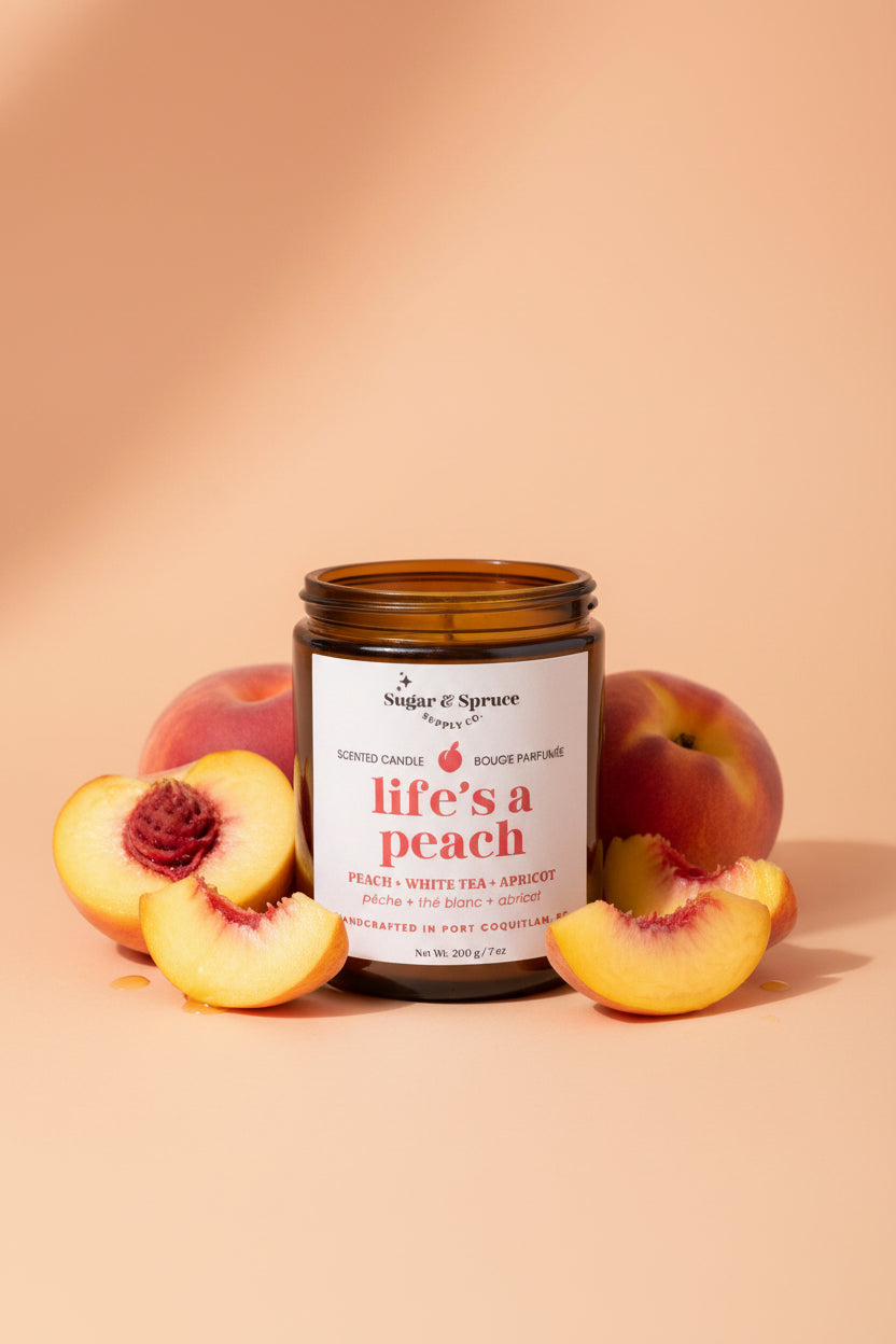 Candle labeled 'life's a peach' with peaches around on a beige background